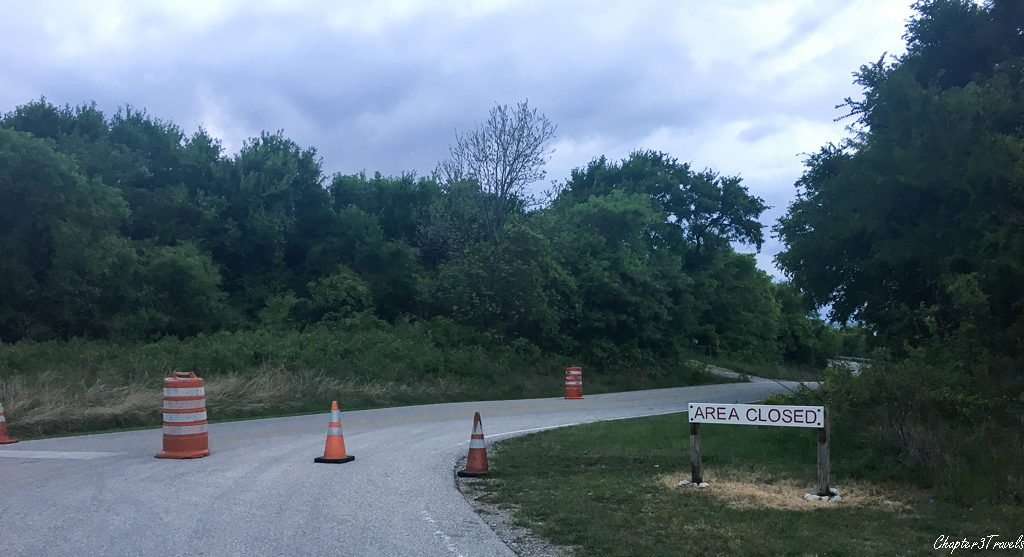 "Area Closed" sign and orange barrels on roadway