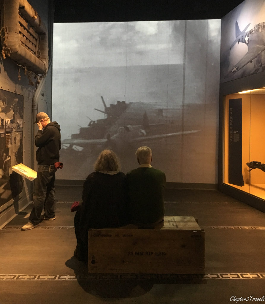 A couple watches a video about aircraft carrier landings during the war