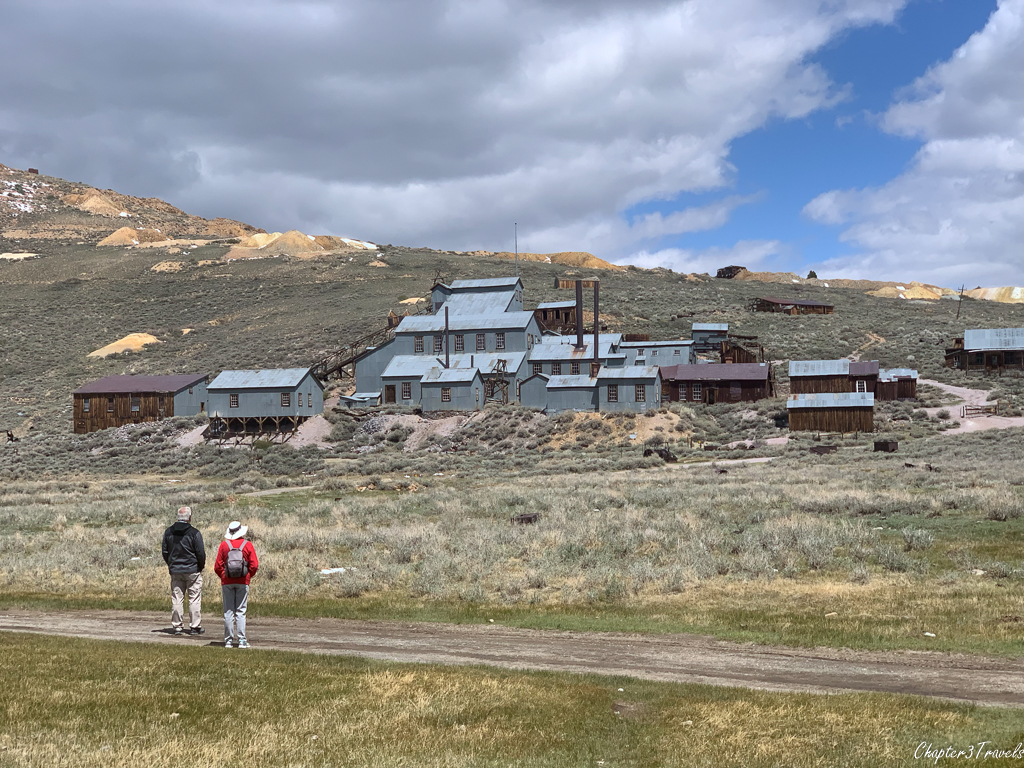 Two visitors looking up at the Bodie stamp mill